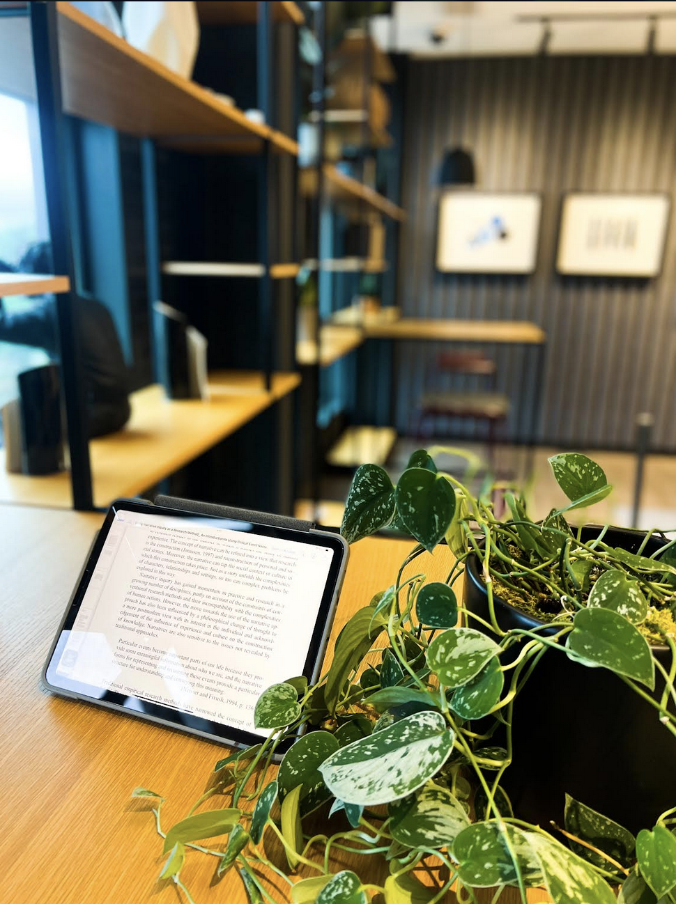 A tablet resting on a desk next to a green plant
