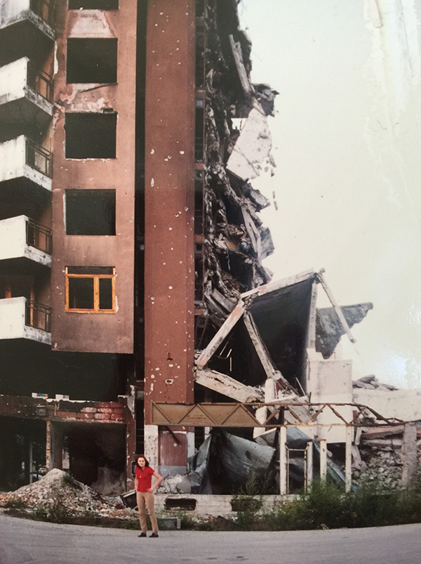 Amra Sabic-El-Rayess standing in front of a bombed-out building in Sarajevo